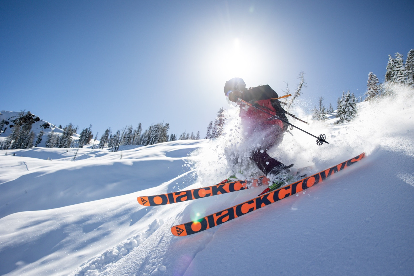 Skier descending a snowy slope under a bright sun.